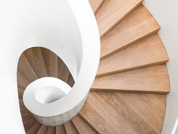 Wendeltreppe aus Holz mit einem weißen Geländer, nach unten fotografiert