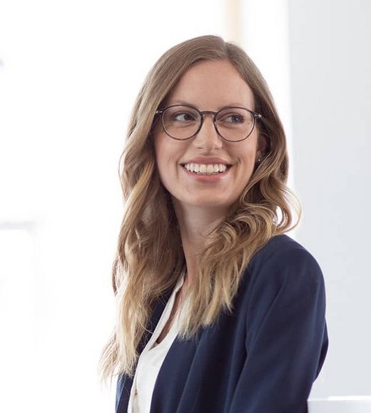 Eine Frau lächelt und steht vor zwei Fenstern