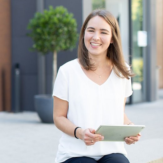 Drei Personen stehen vor dem Standort Reutlingen und unterhalten sich, in der Spiegelung eines Gebäudes ist das RWT-Logo zu sehen