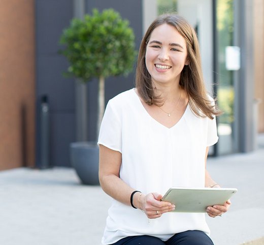 Drei Personen stehen vor dem Standort Reutlingen und unterhalten sich, in der Spiegelung eines Gebäudes ist das RWT-Logo zu sehen